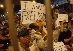 Protesters hold up signs during an evening rally attended by thousands in front of the government headquarters in Hong Kong