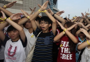 Scholarism founder Joshua Wong (C) and other members chant slogans during a flag raising ceremony in Hong Kong