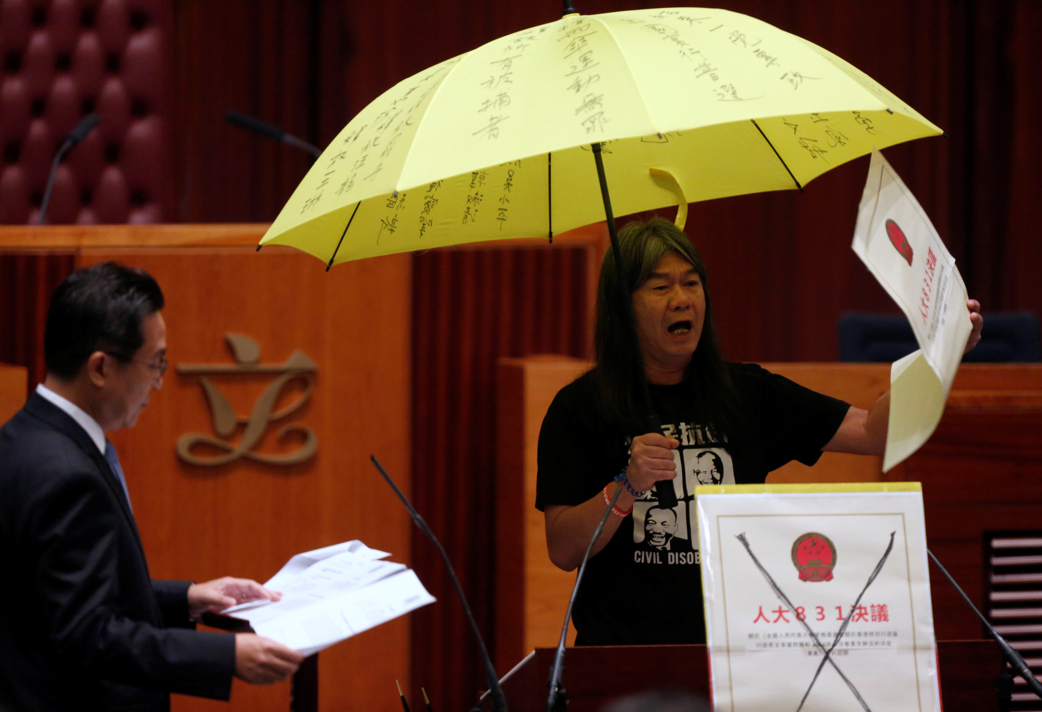 Tân Nghị Sĩ Leung Kwok-hung cầm một chiếc dù, biểu tượng phong trào ủng hộ dân chủ của Hồng Kông (hình của Reuters).